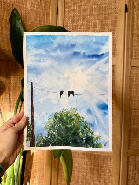 Zwei Vögel sitzen auf einer Stromleitung vor einem sonnigen Himmel und einem Baum.