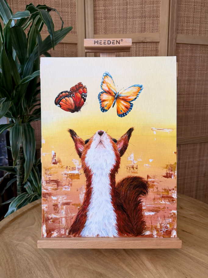 Eine Katze blickt zu zwei schwebenden Schmetterlingen vor einem orangefarbenen Hintergrund.