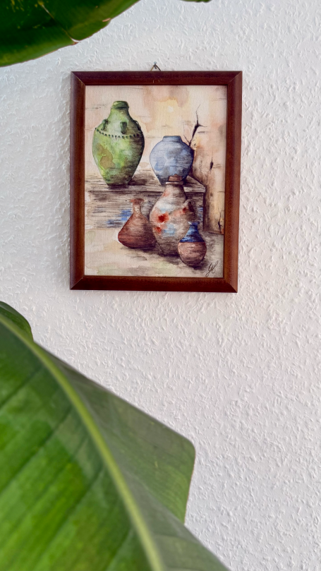 Ein gerahmtes Bild von Töpfen in verschiedenen Farben, umgeben von Pflanzenblättern.