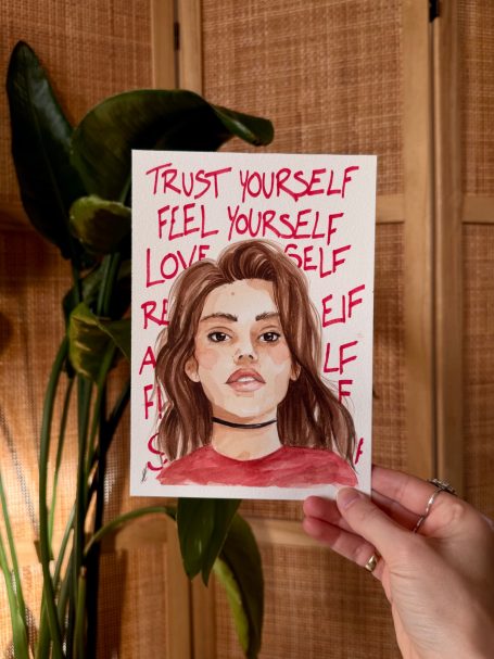 Porträt einer Frau mit langen Haaren in einem roten Oberteil, umgeben von grünen Pflanzen.