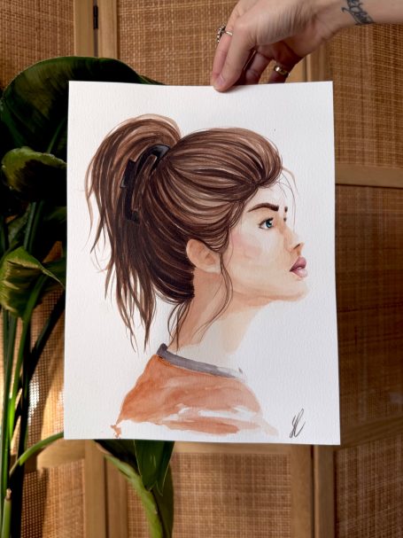 Porträt einer Frau im Profil mit braunem Haar, braun-orangefarbener Kleidung und neutralem Hintergrund.