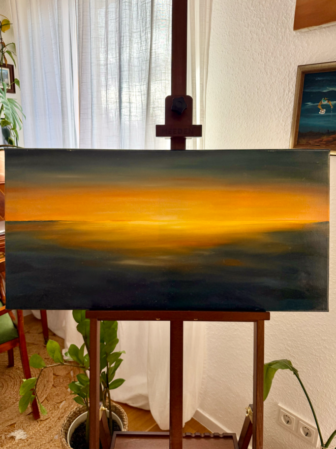 Ein farbenfroher Sonnenuntergang über dem Wasser, mit orange und gelben Tönen.